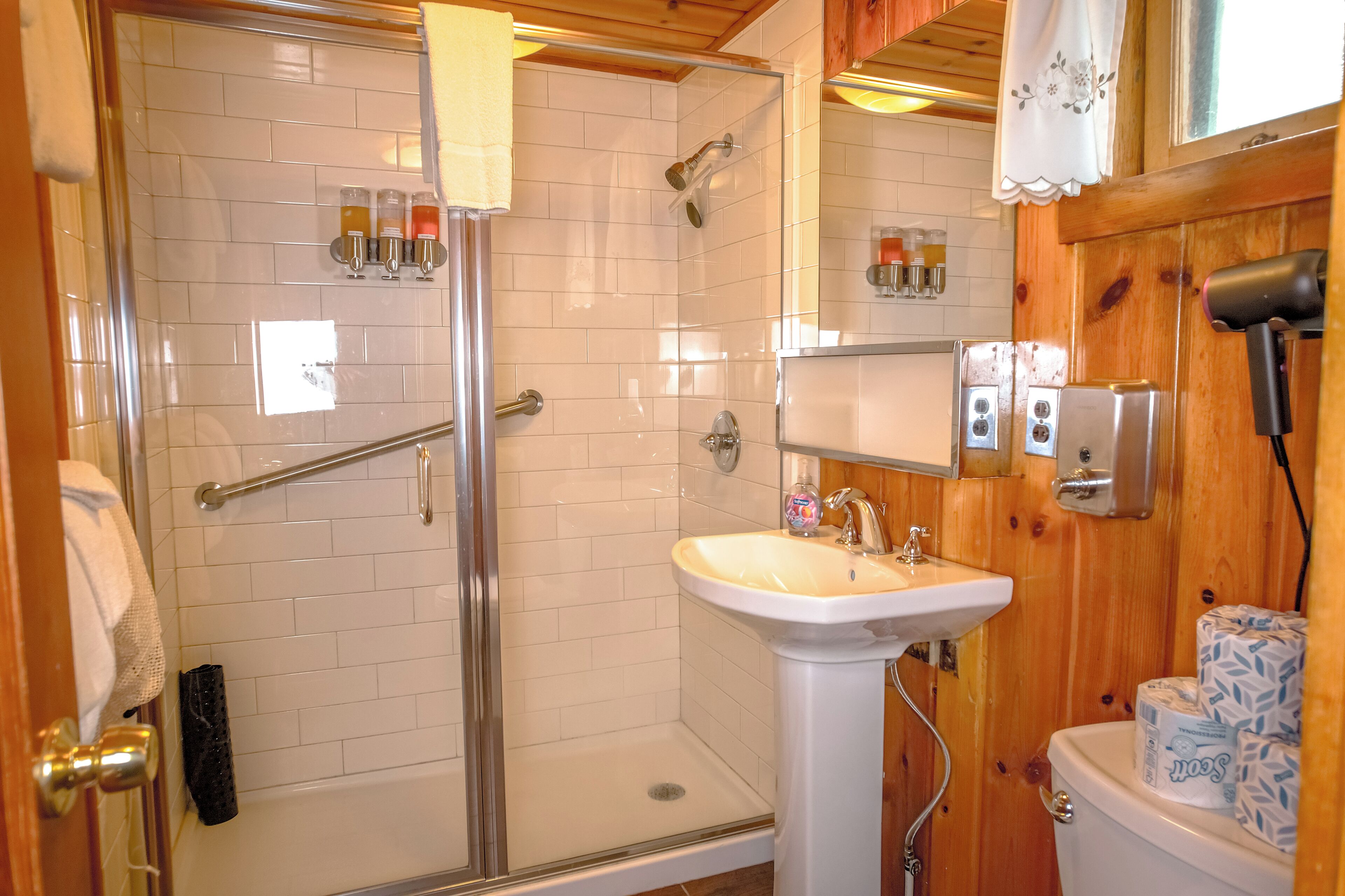 A bathroom with a glass shower enclosure, a white sink, and a toilet.
