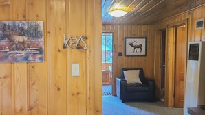 A wooden interior with a painting of a deer, a sign with the word 'KEYS', a black leather sofa, and a television. - Idlewilde by the River (Estes Park)