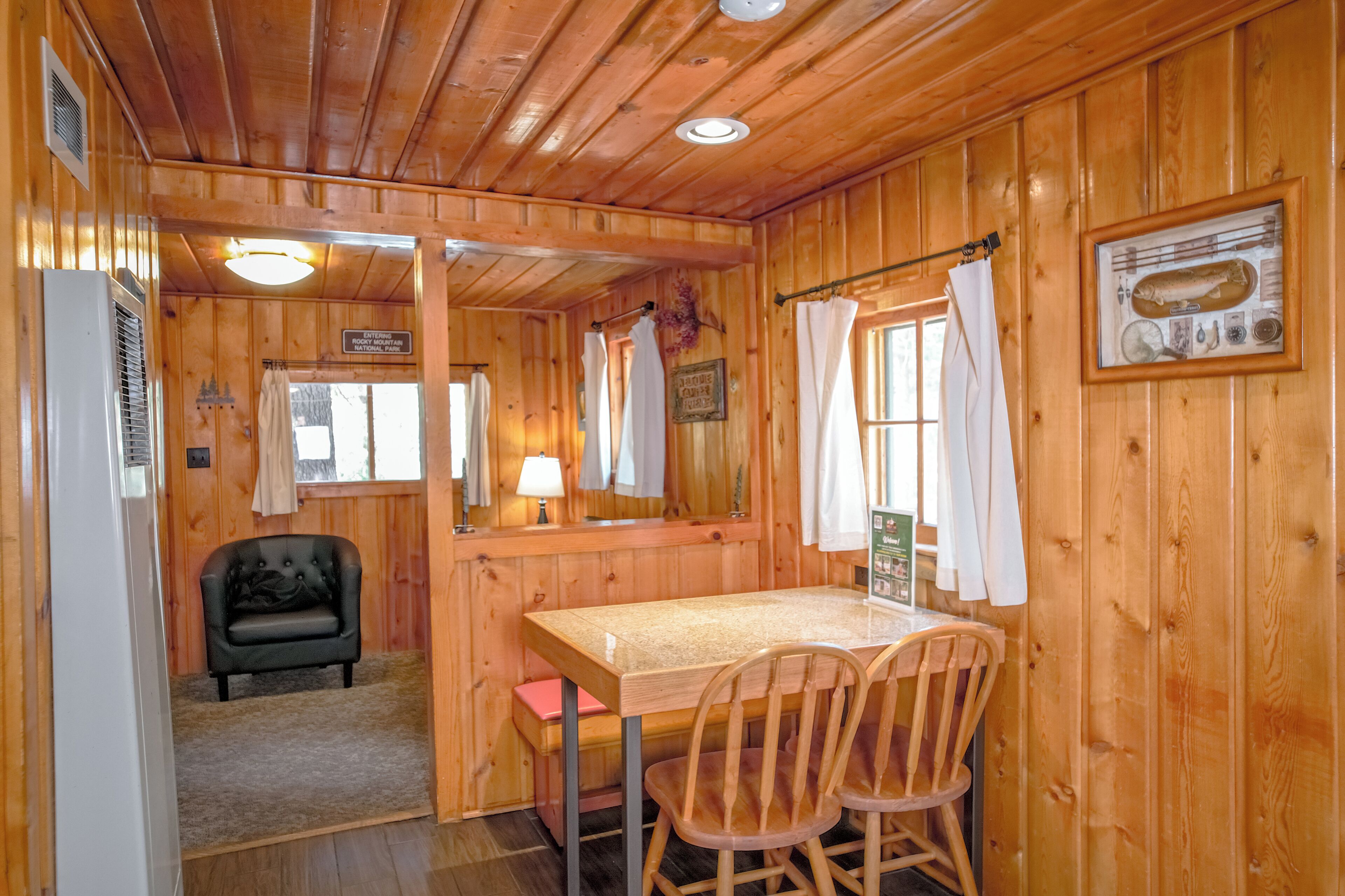 Ein Holzblock-Interieur mit Esstisch, Stühlen, einer Couch und einer Wandfischsammlung.