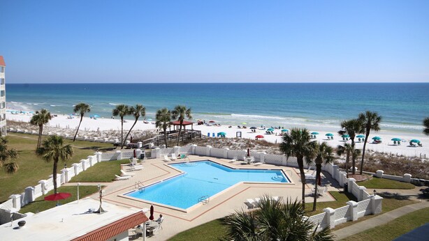 Een resort met een zwembad, toegang tot het strand en palmbomen.