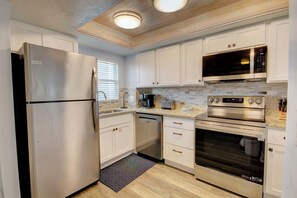 A modern kitchen with stainless steel appliances, white cabinetry, and a tiled backsplash. - El Matador 358 -  FREE TICKETS!! Your stay includes free tickets to many area attractions! (Fort Walton Beach)