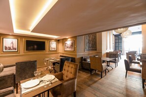 A restaurant with wooden flooring, cushioned chairs, and framed pictures on the walls. - AVENUE SUITES APPART HOTEL - STANDARD (Maarif)