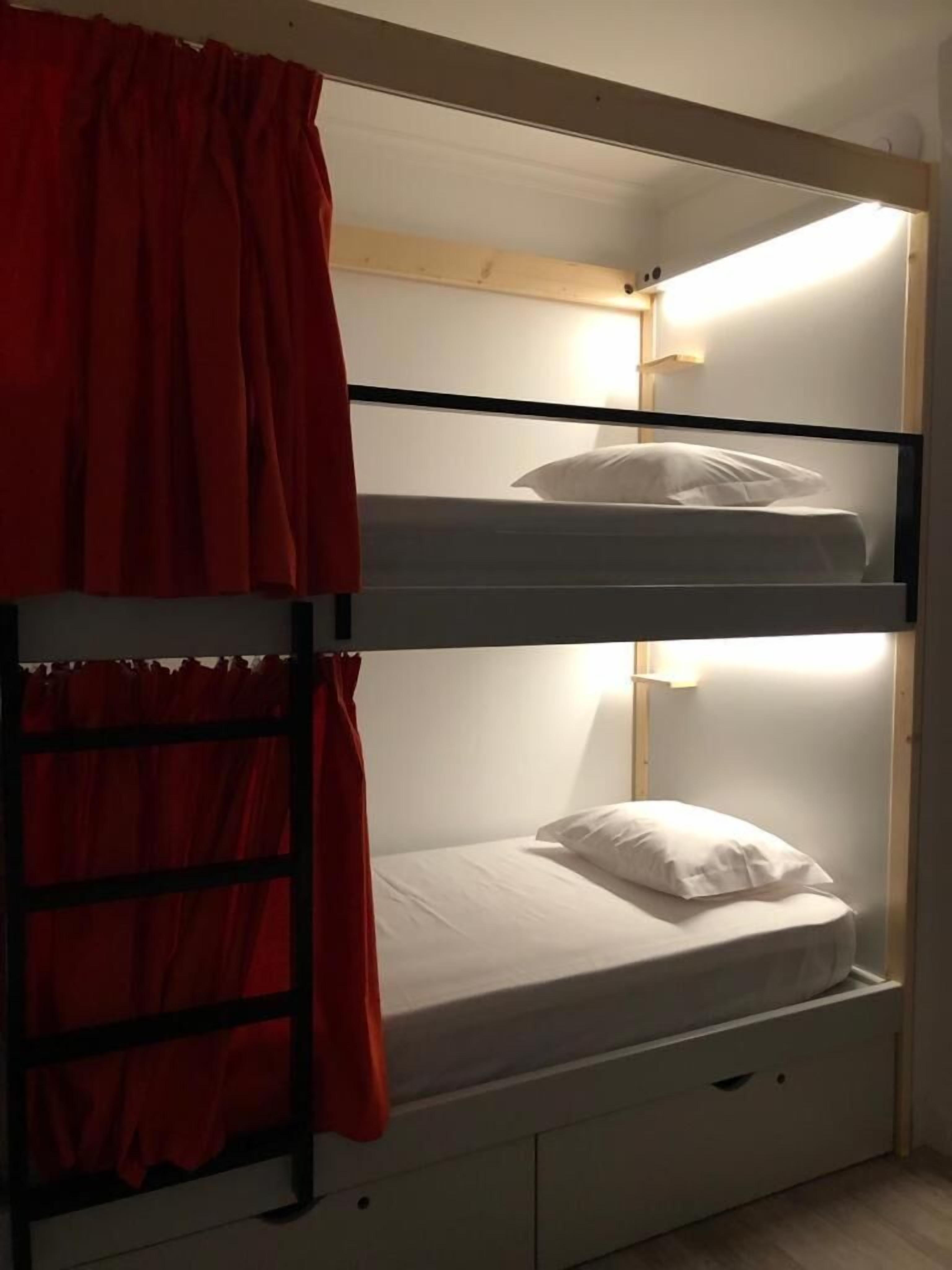 A bunk bed with a ladder, a bedside table, and a nightstand.