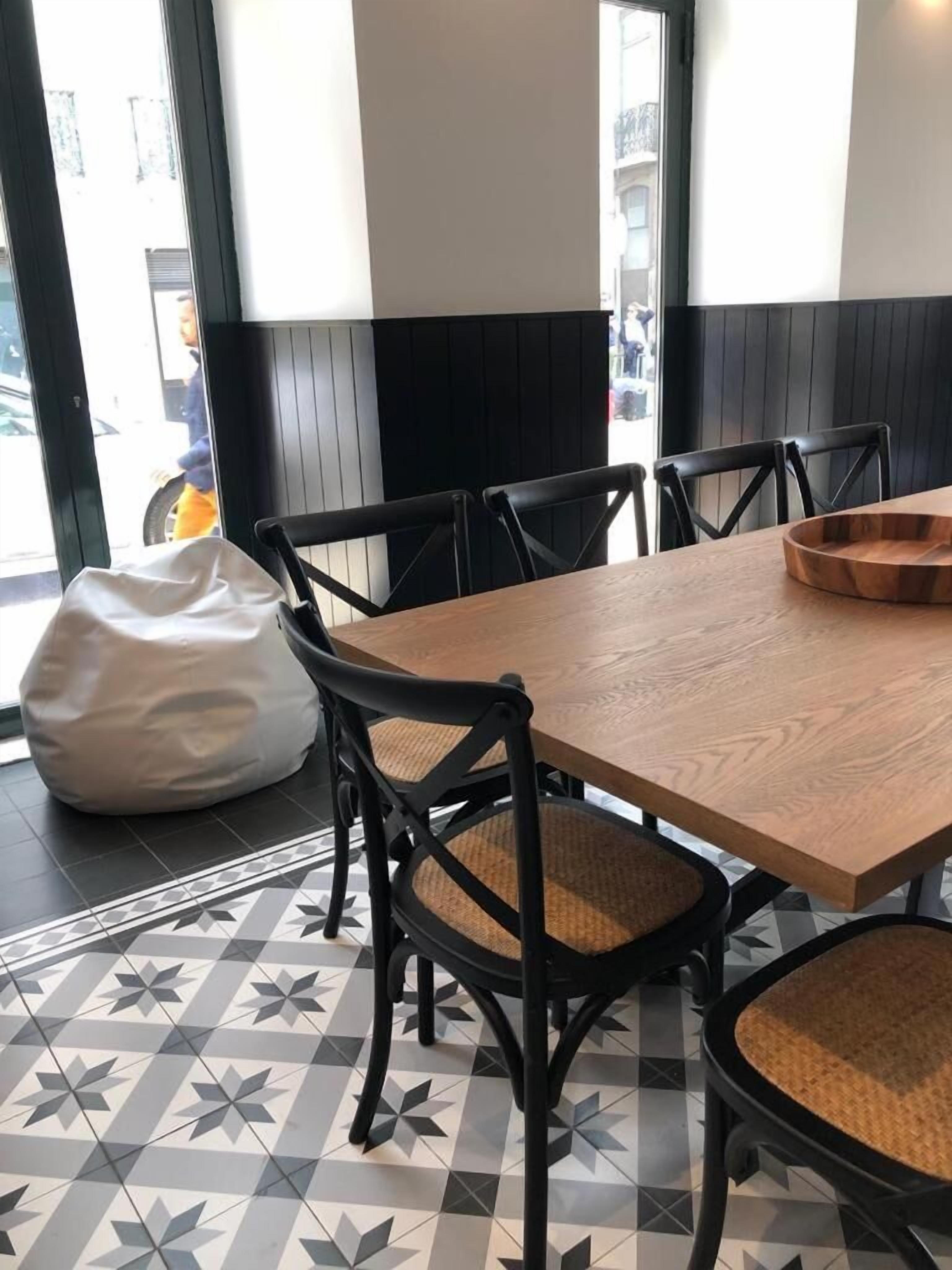 A dining area with a wooden table, black chairs with woven seats, and a white bean bag.