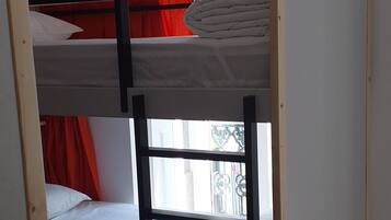 A bunk bed with a wooden frame and red curtains.