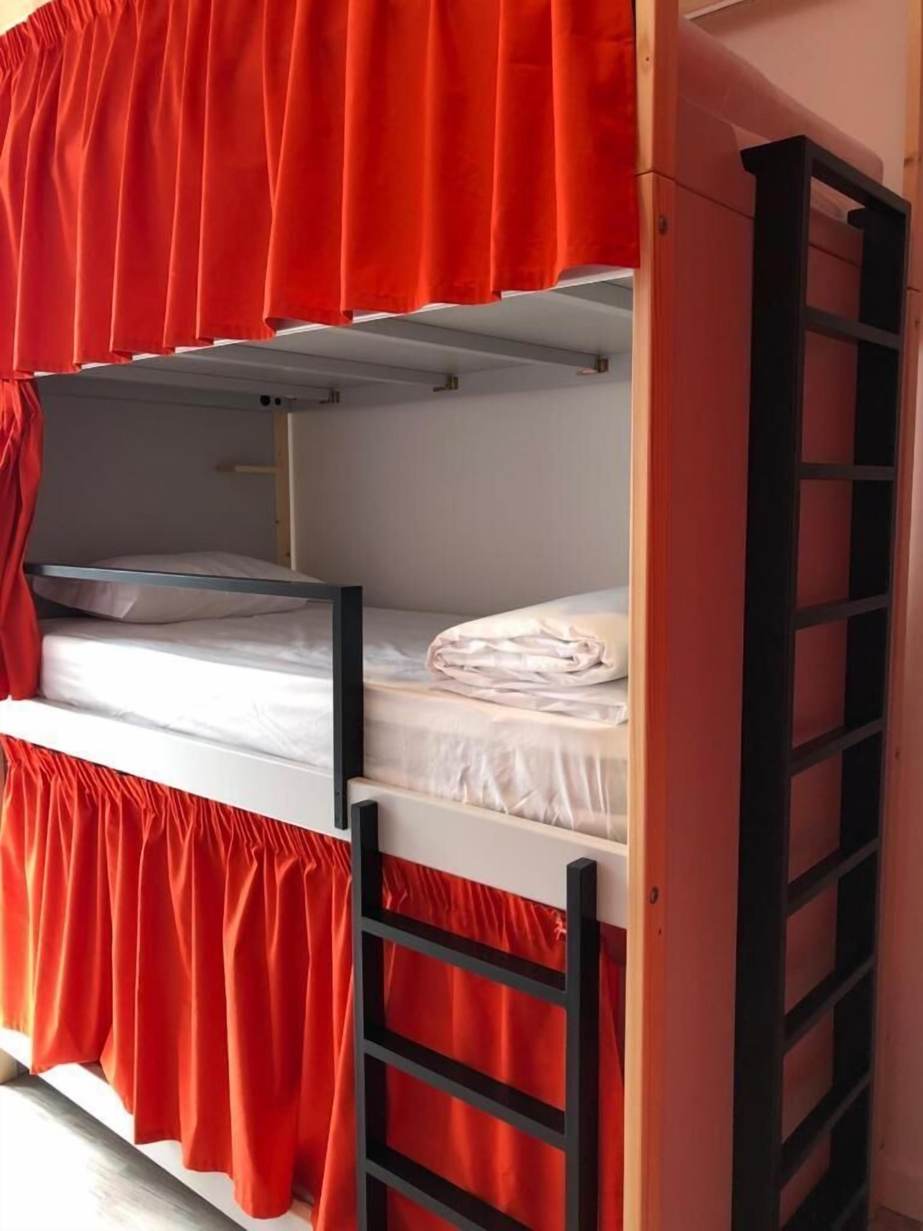 A bunk bed with red curtains and a ladder.