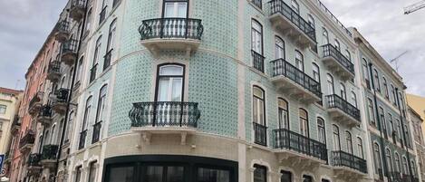 A multi-story building with balconies, large windows, and a corner entrance.