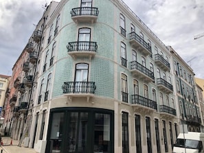 A multi-story building with balconies, large windows, and a corner entrance.
