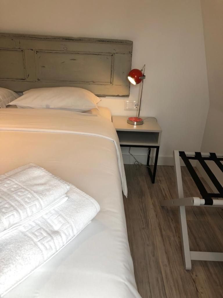 A bedroom with a bed, bedside table, lamp, and a wooden floor.