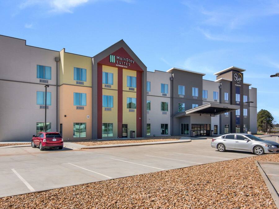 Ein MainStay Suites Hotel mit modernem Design, inklusive Parkplatz und überdachter Zufahrt.