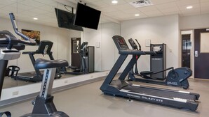 Ein Fitnessstudio mit Laufbändern, Ergometer und einer Spiegelwand.