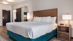 Ein Hotelzimmer mit einem großen Bett, einem Nachttisch mit Lampe und einem Spiegel an der Wand.