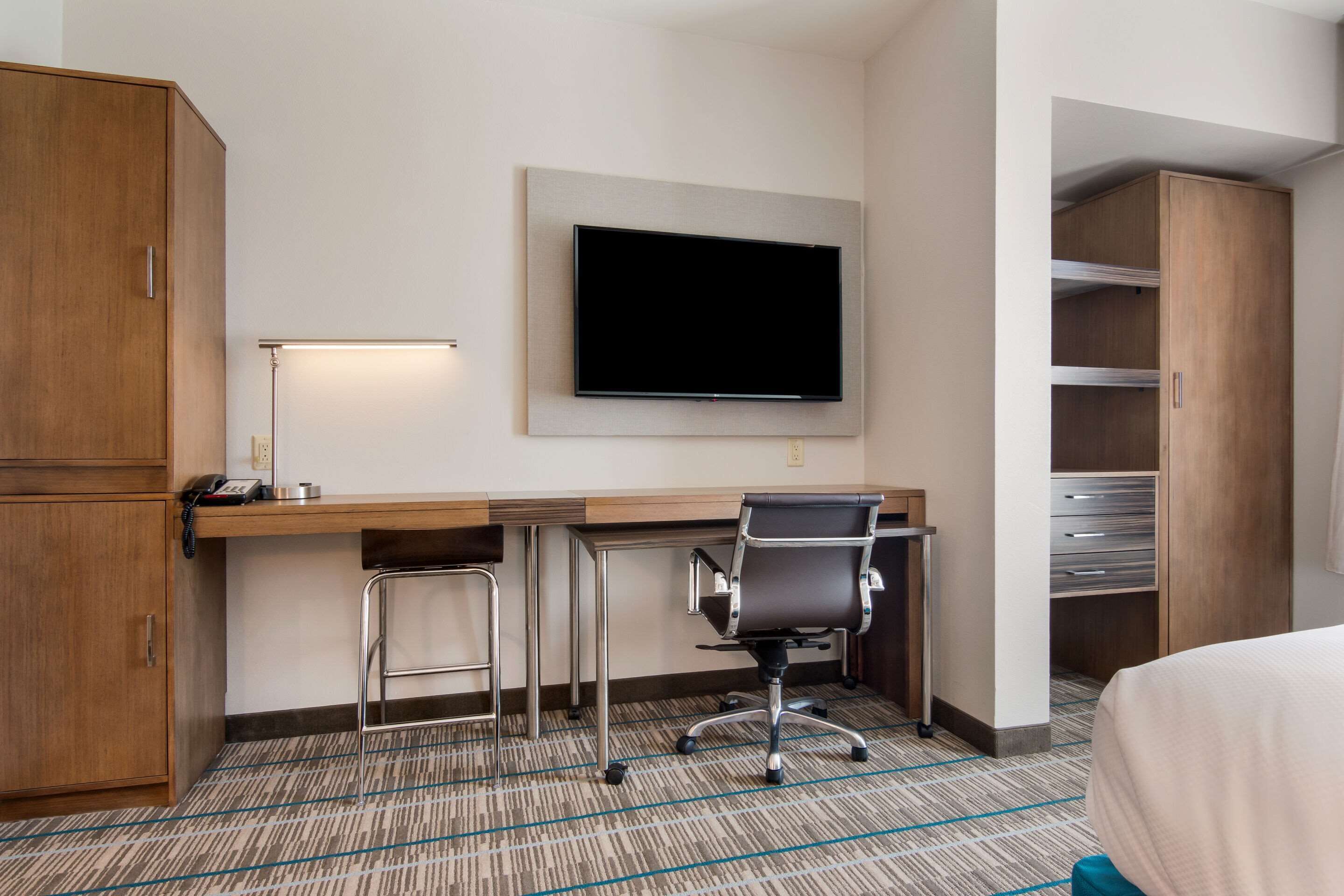 Une chambre d’hôtel équipée d’un bureau, d’une chaise, d’une télévision, d’une armoire et d’un lit.