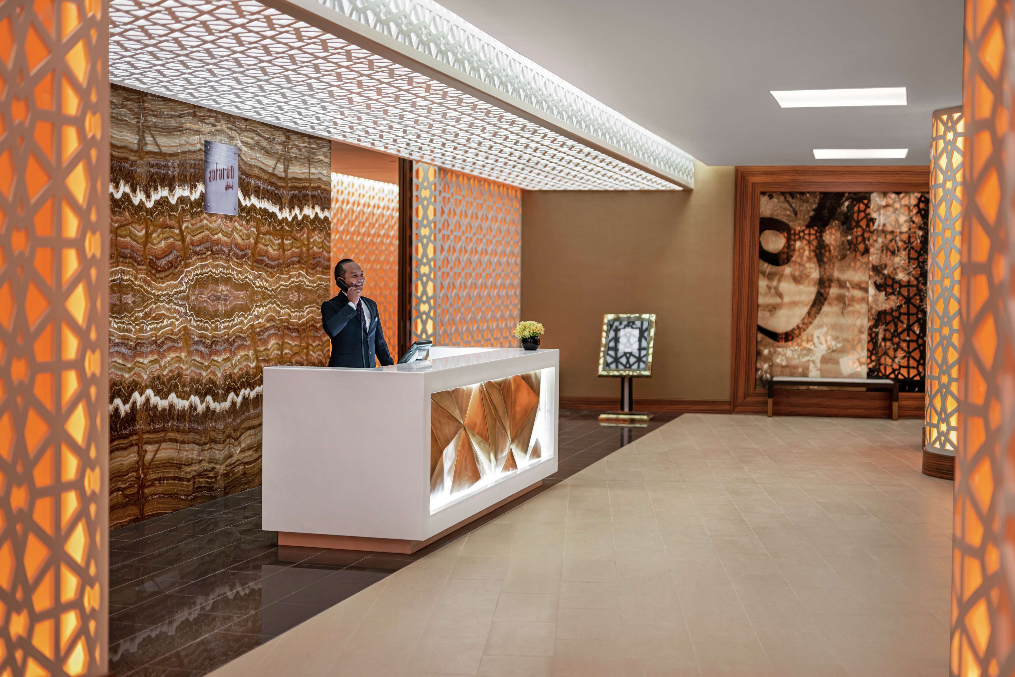 Un espace d’accueil au design moderne, comprenant un comptoir d’accueil, un mur orné de motifs et un éclairage décoratif.