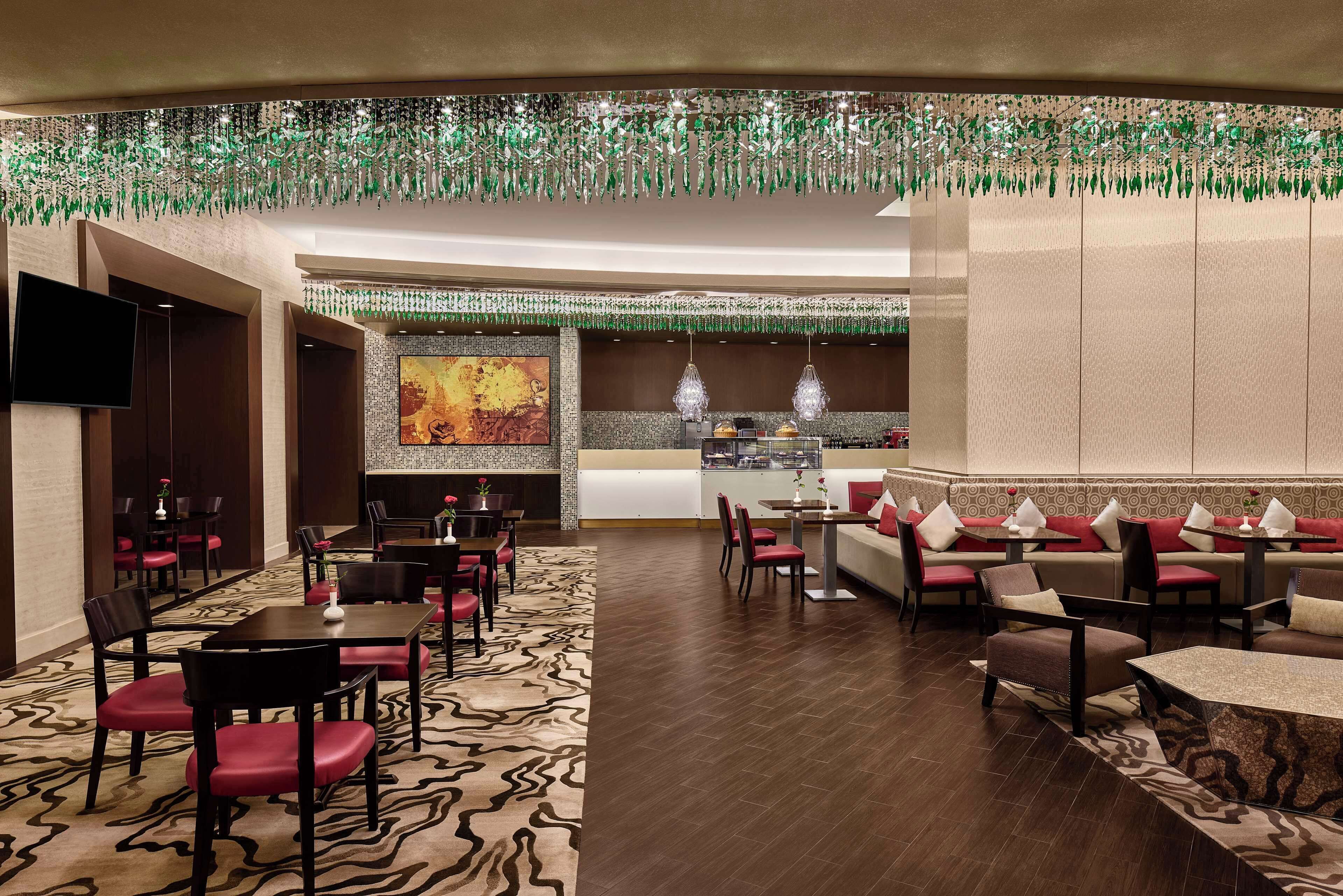 A restaurant with a modern interior, featuring a mix of seating options including booths and tables, a patterned carpet, and a decorative ceiling.