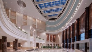A spacious lobby with a high ceiling, a central staircase, and a large open area with a curved wall. - Doubletree by Hilton Jabal Omar Makkah (Makkah)