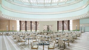 A spacious, multi-level dining area with tiered seating and a high ceiling with skylights. - Doubletree by Hilton Jabal Omar Makkah (Makkah)