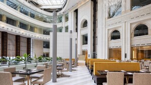 A spacious hotel lobby with a central atrium, multiple seating areas, and a view of the sky through the glass ceiling. - Doubletree by Hilton Jabal Omar Makkah (Makkah)