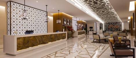 Un moderno vestíbulo de hotel con un mostrador de recepción de diseño geométrico, zona de estar y un plafón con lámpara geométrica.