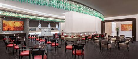 A spacious restaurant with multiple seating areas, including booths and tables, and a bar area with a modern design.
