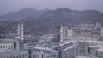 A large, historic building with multiple towers and domes, surrounded by a cityscape and mountains.