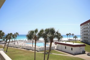 A hotel with a pool, palm trees, and a view of the beach.