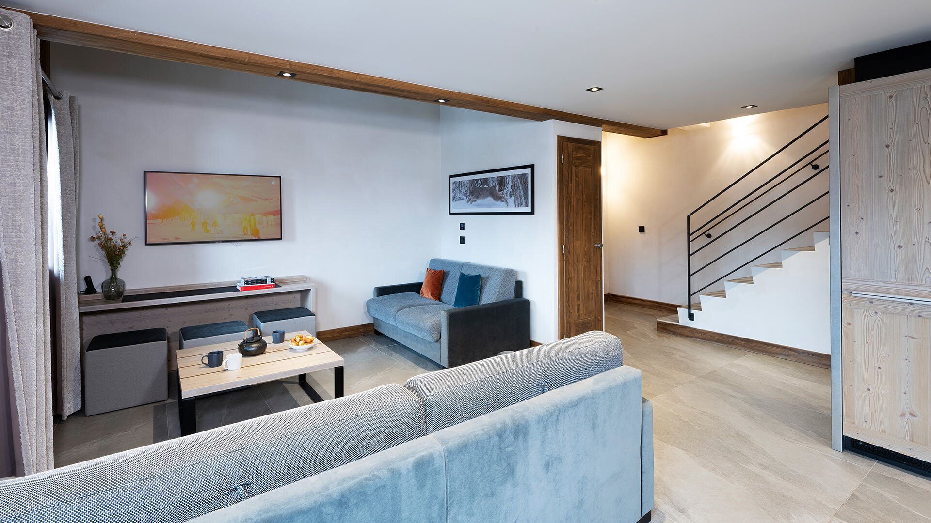Una sala de estar moderna con un sofá, una mesa de comedor y una escalera.