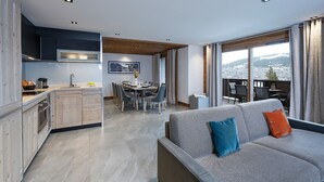 A modern apartment with a kitchen, dining area, and a balcony with a city view. - MGM Hôtels & Résidences – Résidence Amaya (Villard-sur-Doron)
