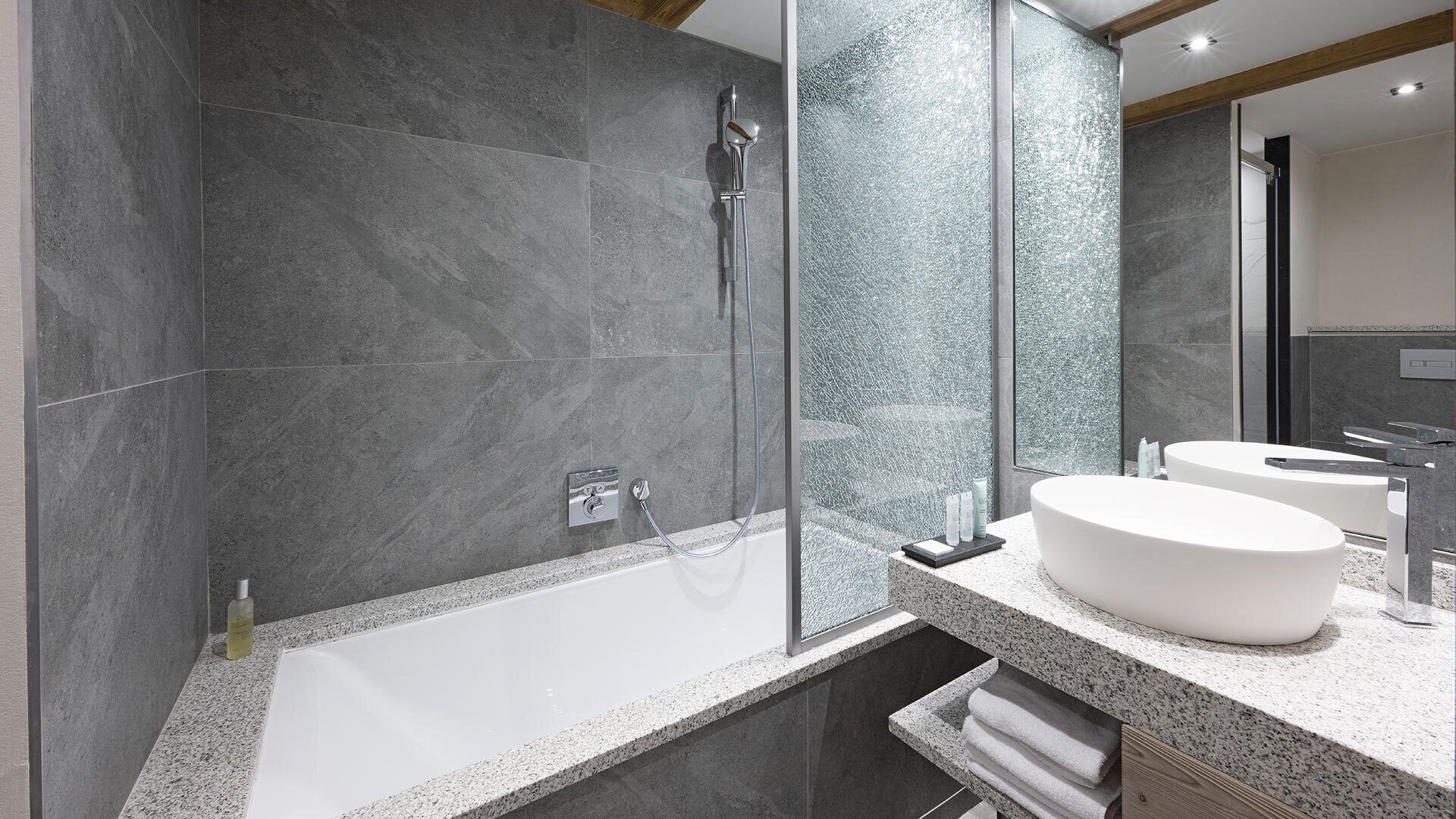 A modern bathroom with a glass-enclosed shower, a freestanding bathtub, and a vanity with two sinks.