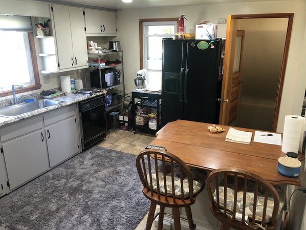 A kitchen with a wooden table, two chairs, a refrigerator, and various kitchen appliances. - Perfect location!!! Blocks from Lambeau Field. (Green Bay)