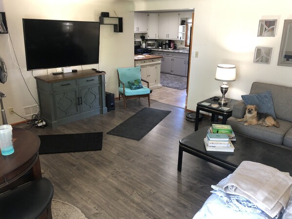 A living room with a flat-screen TV, a sofa, a coffee table, and a dog. - Perfect location!!! Blocks from Lambeau Field. (Green Bay)