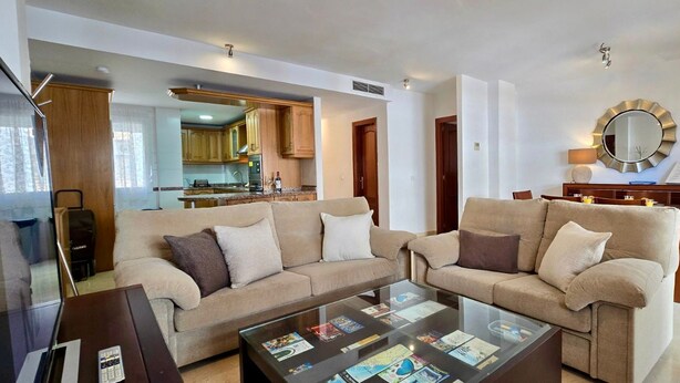 A living room with a sofa, coffee table, and a dining area with a table and chairs. - Urban 2 BR apartment : Pool : Los Boliches (Fuengirola)