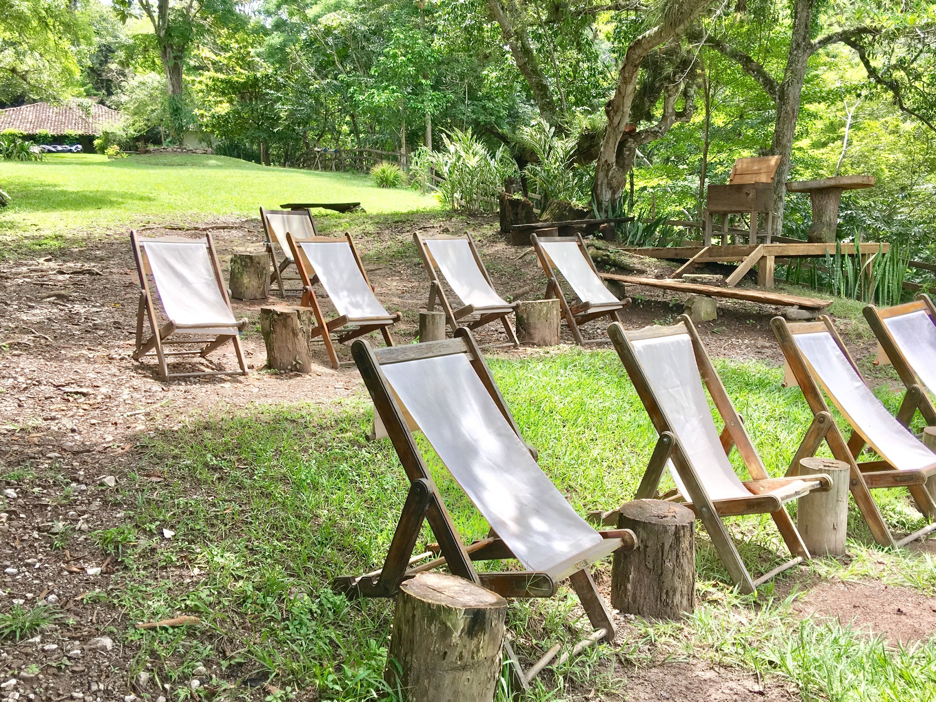 Un jardín con sillones de madera distribuidos alrededor de una estructura central de madera.