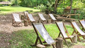 Un jardín con sillones de madera distribuidos alrededor de una estructura central de madera.
