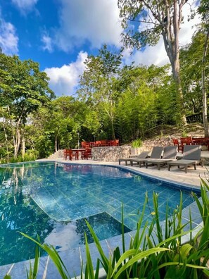 A clear swimming pool surrounded by lush greenery and stone walls. - Hotel Hacienda San Lucas (Copan Ruinas)