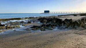 Ein Strand mit Felsen, einem Steg und dem Meer.