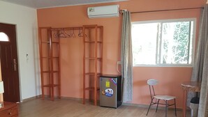 Une chambre à coucher comprenant un lit, un bureau, une chaise, une armoire et un appareil de climatisation.