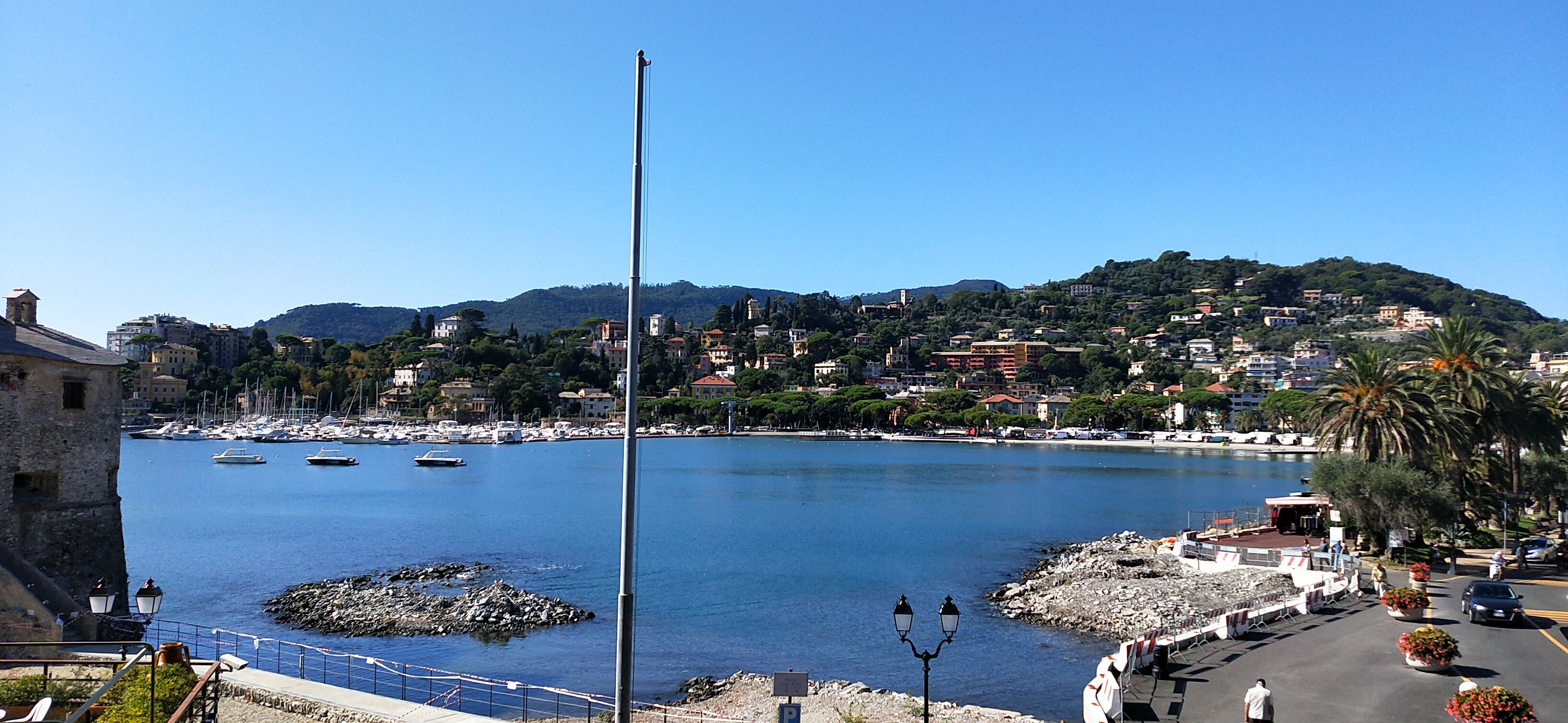 A coastal town with a marina, stone buildings, and a clear blue sky.