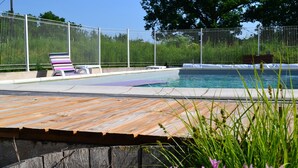 A wooden deck with a pool, surrounded by a metal fence and a tree. - Couanac, cottage in the countryside with swimming pool (Cayriech)