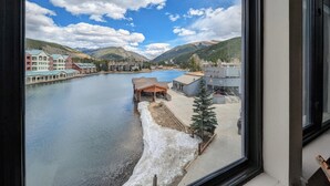 Une vue sur une rivière, avec des bâtiments sur la rive opposée, un petit quai et une zone enneigée au premier plan.
