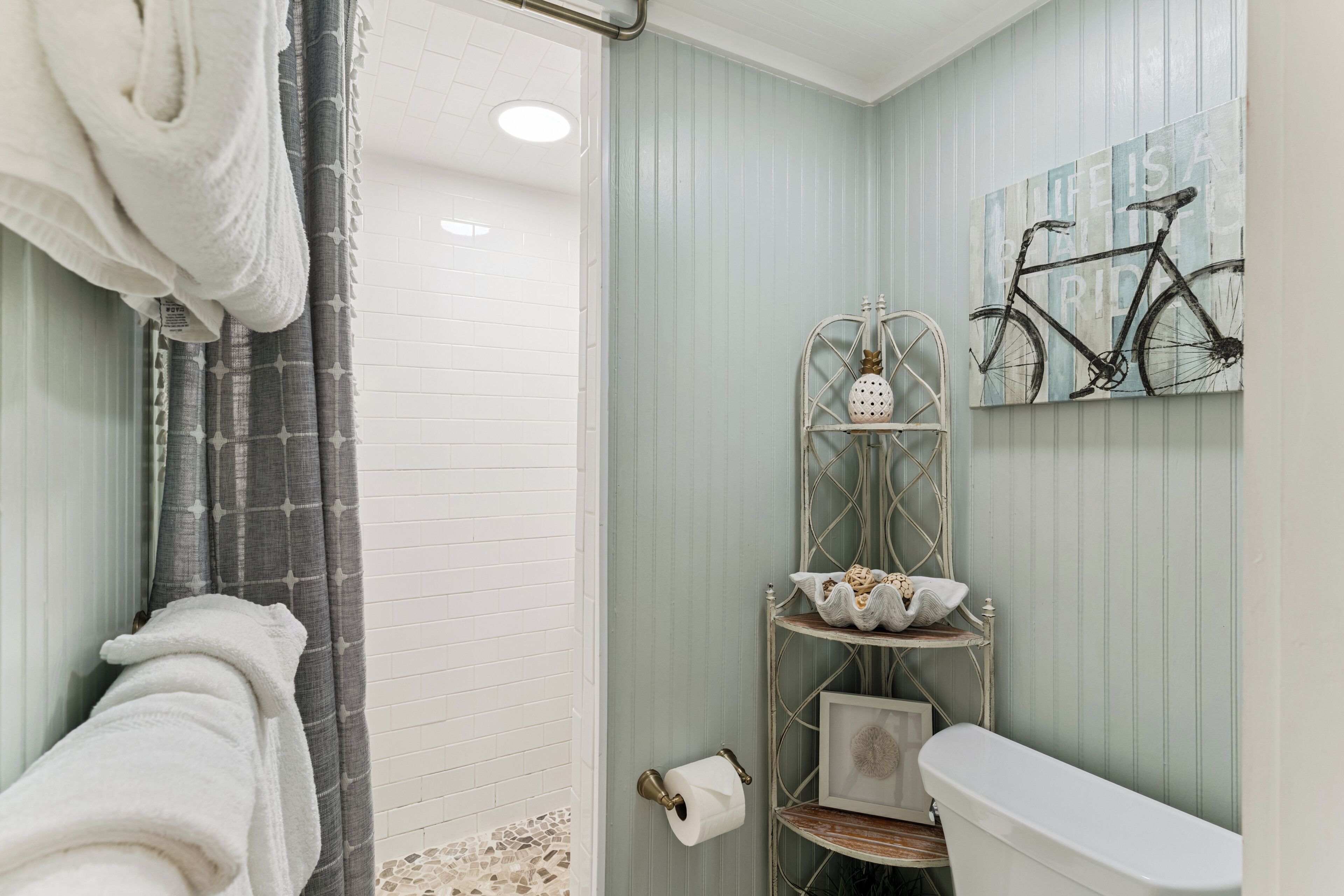 A bathroom with a shower, toilet, and a towel rack.