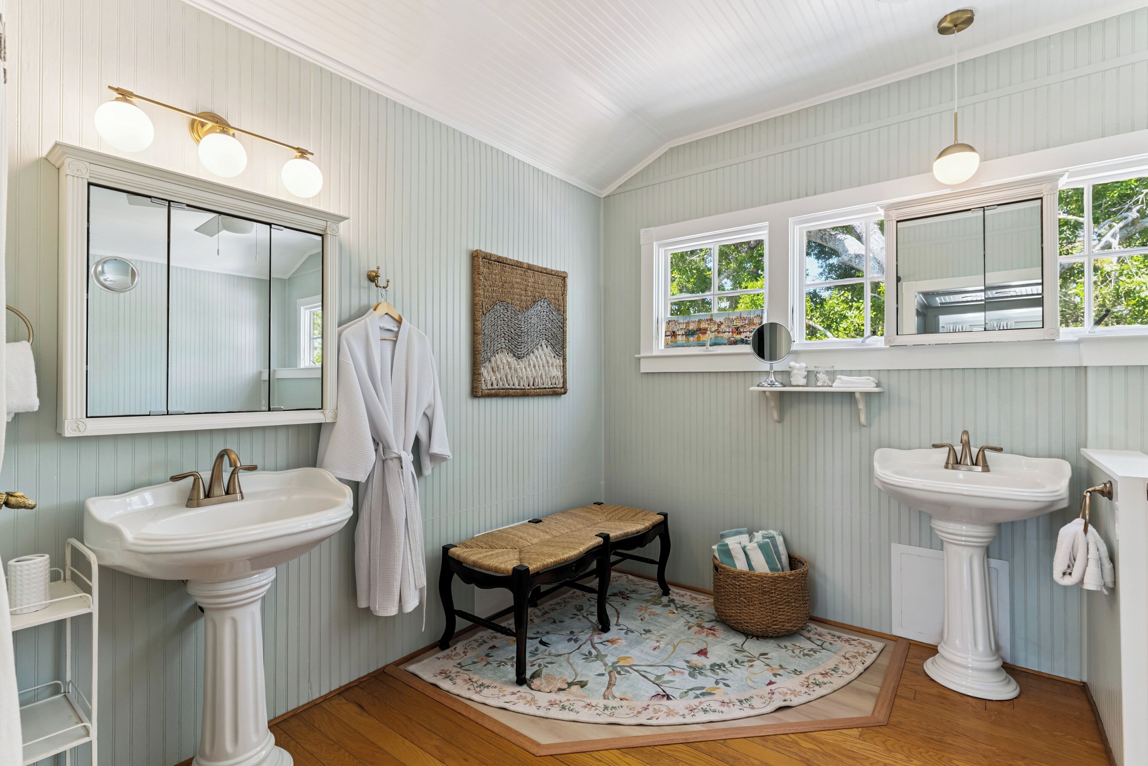 A bathroom with two sinks, a large mirror, and a bench.