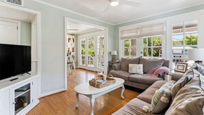A living room with a television, a sofa, a coffee table, and a ceiling fan.