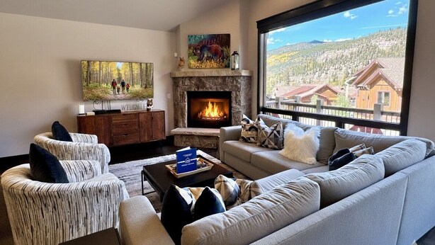 A modern living room with a fireplace, a large window with a scenic view, and a cozy seating area. - Scenic Keystone Retreat | Private Hot Tub (Keystone)