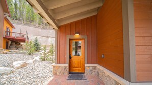 A wooden door with a stone foundation, a brick pathway, and a wooden deck with a railing. - Scenic Keystone Retreat | Private Hot Tub (Keystone)