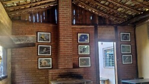 Un interior rústico de ladrillo con un horno de leña, mesas de madera y cuadros en las paredes.