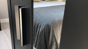 Une chambre à coucher avec un lit, une tête de lit noire et une couvre-lit grise.