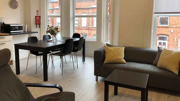 Un salon moderne avec un canapé marron foncé, une petite table basse et un coin repas comprenant une table et des chaises noires.