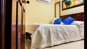 Een hotelkamer met een bed, een schilderij aan de muur en een airconditioning.