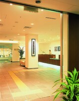 Zona de recepci ón de un hotel, con mostrador, escalera y una planta en maceta.